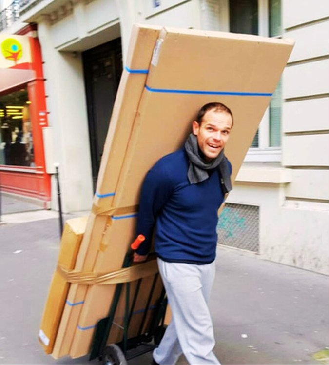 Patrick Pinot dans la rue, un diable chargé de cartons à la main